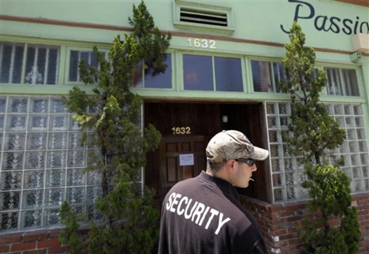 A security guard who declined to give his name stands outside House of Kush, a closed medical marijuana shop in the Eagle Rock area of Los Angeles. 